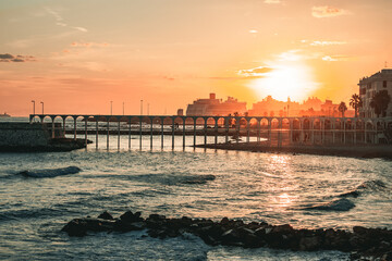 Sunset with close up view of the bridge over the sea with ships in the background. Civitavecchia, Italy