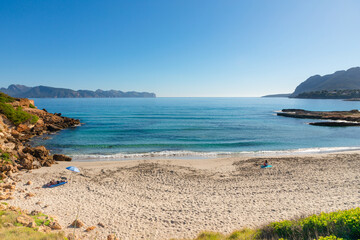 Playa de Sant Joan, en el Mal Pas de Alcudia, en el norte de la isla de Mallorca. Con una sombrilla y una persona en su toalla tomando el sol.