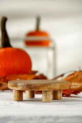 Marble pedestal on a white wooden table in the composition of autumn, free space