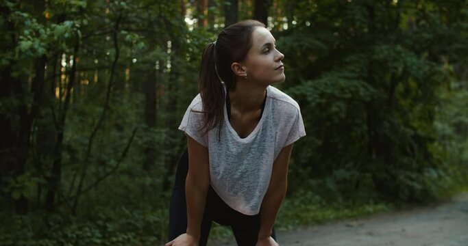tired woman runner finishes her run in the forest. High quality 4k footage