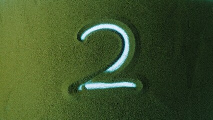 Hand drawing Number Two 2 Symbol in the Green Sand. Male hand writes a number on the green sand with backlight. It is a series from 0 to 10. Top view 4k resolution