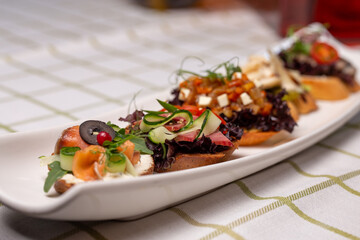 Bruschetta with various fillings, a variety of small sandwiches on a white plate