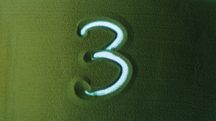 Hand drawing Number Three 3 Symbol in the Green Sand. Male hand writes a number on the green sand with backlight. It is a series from 0 to 10. Top view 4k resolution