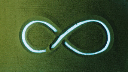 Hand drawing the Infinity symbol in the Green Sand. Male hand writes the Infinity symbol on the green sand with white backlight. Top view 4k resolution