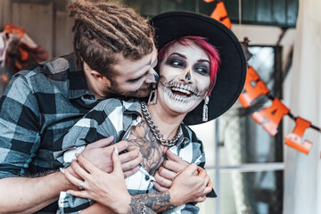 Scary love romantic family couple man,woman celebrating halloween.Terrifying black skull half-face makeup,witch costumes.Stylish images,jacket,hat.Fun at photoshoot,holiday party. Decorating of porch