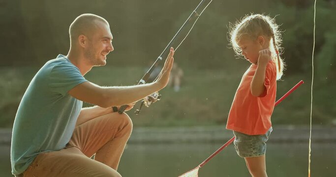 Dad encourages the child, the girl was upset because of an unsuccessful catch, a man with a fishing rod near the lake in the park.