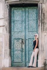 A young, blonde girl in a black blouse and sunglasses poses against the backdrop of an old courtyard in Lviv. Ukraine.