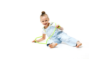 Little girl dressed in denim overalls with jumping rope on a white background.