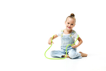Little girl dressed in denim overalls with jumping rope on a white background.