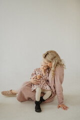Mom kisses and hugs her daughter in the studio.