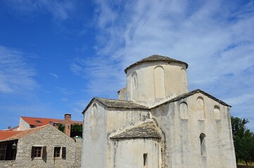 Fototapeta na wymiar Back and right view of one of the oldest churches in Croatia, pre-romanesque Church of The Holy Cross in Nin. Summer partially cloudy day, scattered clouds. 