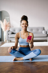 Home Sport. African american woman atching online tutorials on laptop and training on yoga mat in living room and enjoying fitness and healthy lifestyle