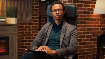 Portrait of african american psychoanalyst taking notes on papers to help with relationship problems and guidance advice. Psychologist starting therapy session meeting, doing counseling visit.