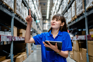 Women warehouse worker using digital tablets to check the stock inventory in large warehouses, a...