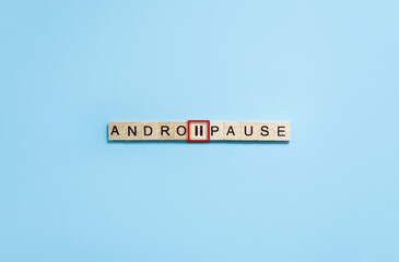 Andropause word and pause sign on wooden blocks with lettering on blue background. Minimal concept...