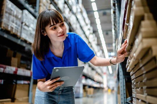 Women warehouse worker using digital tablets to check the stock inventory in large warehouses, a Smart warehouse management system, supply chain and logistic network technology concept.