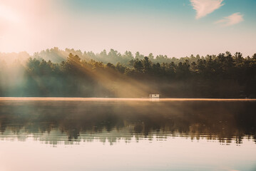 Beautiful light rays shining on a calm lake in the early morning.