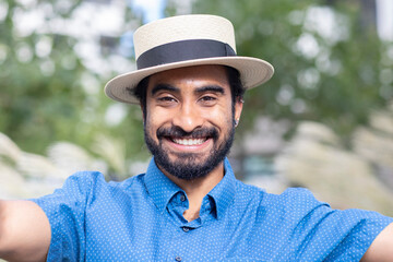 young man with beard and summer hat outside laughing