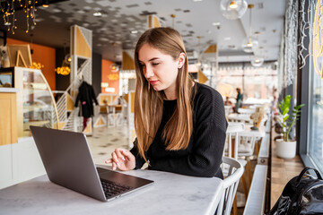 young girl sitting in a cafe with a laptop
