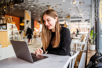 young girl in a cafe sitting at a laptop
