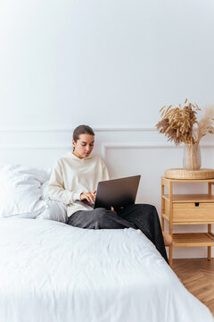 Young girl watching a movie on a laptop lying on a bed in a brig