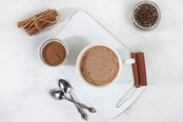 Coffee drink with milk and whipped cream, cappuccino coffee, latte, cinnamon, coffee beans on a gray concrete table, modern coffee shop advertisement, selective focus, top view,