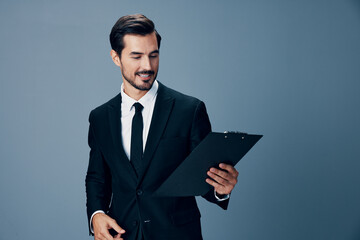 Portrait of a business man in a stylish suit smile with tie beautiful face on a blue isolated background with a tablet in his hands. Business concept young businessman startup copy place