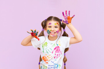 A child stained in multicolored paints will have to be creative. The concept of children's creativity on a pink isolated background.