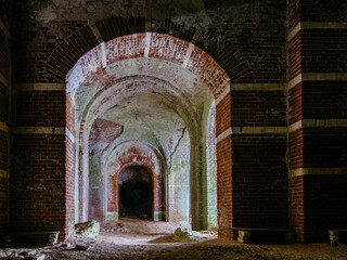 Naklejka premium Dark corridor of old ancient abandoned red brick ruined historical building