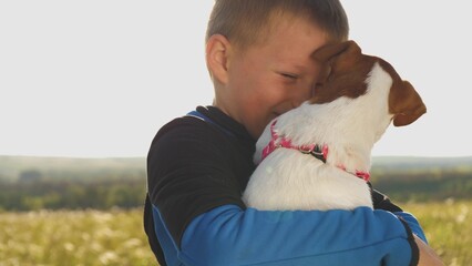 happy family. little boy kisses dog. toddler boy holds beloved pet his arms smiles. since...