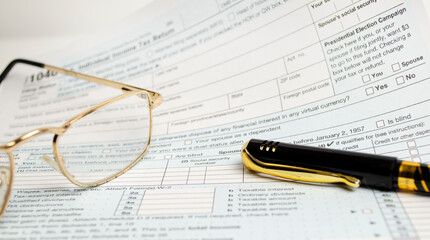 Tax return form with glasses and pen on white background