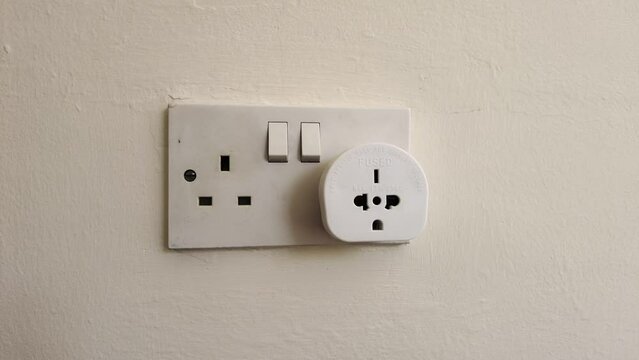Plug in electrical appliance with adapter and switch on, UK British socket, european adapter