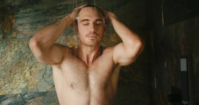 Young man enjoys taking care of body in brown tiled shower