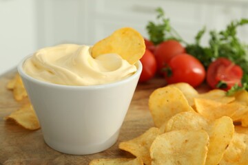Potato chips and mayonnaise on wooden board, closeup