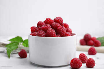 Bowl with fresh ripe raspberries on white marble table
