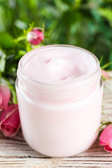 Jar of hand cream and roses on white wooden table, closeup
