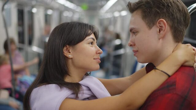 Close-up. A guy and a young woman are riding the subway, standing, hugging, looking into each other's eyes, smiling. Subway car, communication, relationships. Slow motion 120fps footage