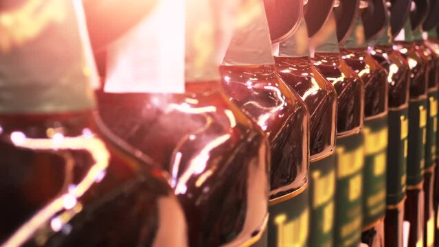 Bottles of whiskey, brandy or Scotch line up on the shelves of a liquor store or ABC store. Close-up shot