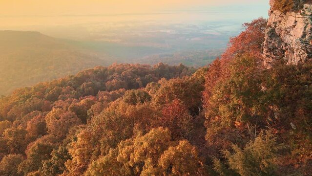 Mountain cliff arial view during autumn color early morning sun light over a colorful Arkansas forest wilderness from drone vantage point
