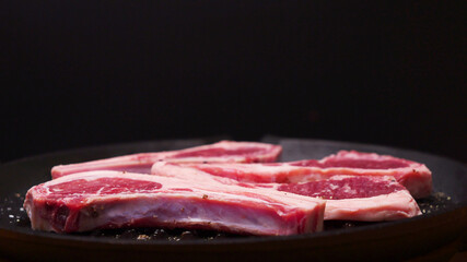 Close-up of steak and salt on pan, black background.