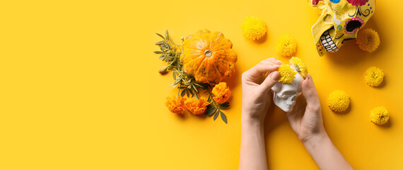 Hands with human skulls, flowers and pumpkin on yellow background. Mexico's Day of the Dead (El Dia de Muertos) - obrazy, fototapety, plakaty