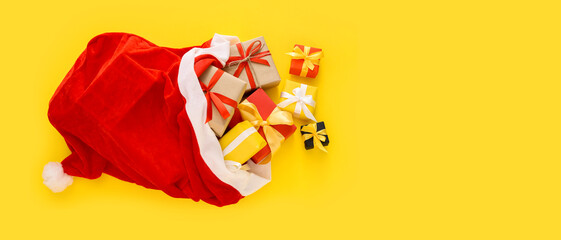 Santa Claus bag full of gifts on yellow background with space for text, top view