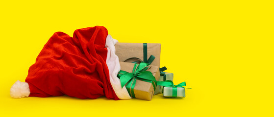 Santa Claus bag full of gifts on yellow background with space for text