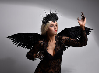 portrait of beautiful  model  wearing black gothic dress with headdress  and feathered angel wings....