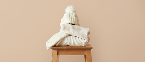 Stylish winter clothes on table against beige background
