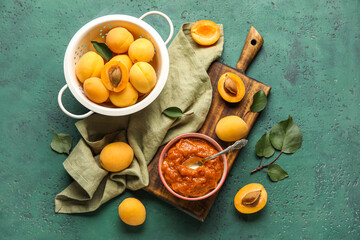 Composition with bowl of tasty apricot jam, fruits and leaves on color background