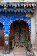 Fototapeta na wymiar Traditional wooden door and blue coloured house of Jodhpur city, Rajsthan, India. Historically, Hindu Brahmins used to paint their houses in blue for being upper caste, the tradition follows.