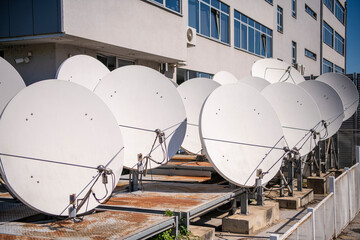 Row of Many white parabolic satellite antenna dishes. - obrazy, fototapety, plakaty