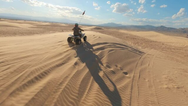 FPV drone shot of an ATV rider riding quads through desert kicking up dust in the air near las vegas Nevada.A Rider doing stunts and enjoying outdoor sports. 4K UHD