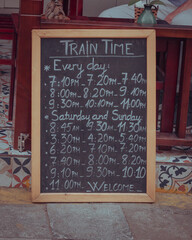 a chalkboard indicating train times on Train Street, Hanoi